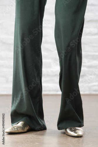 Female model wearing linen pine green casual trousers. Studio shot.