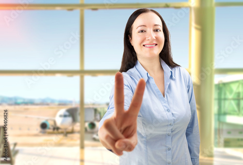 Confident young woman making a peace gesture at airport.