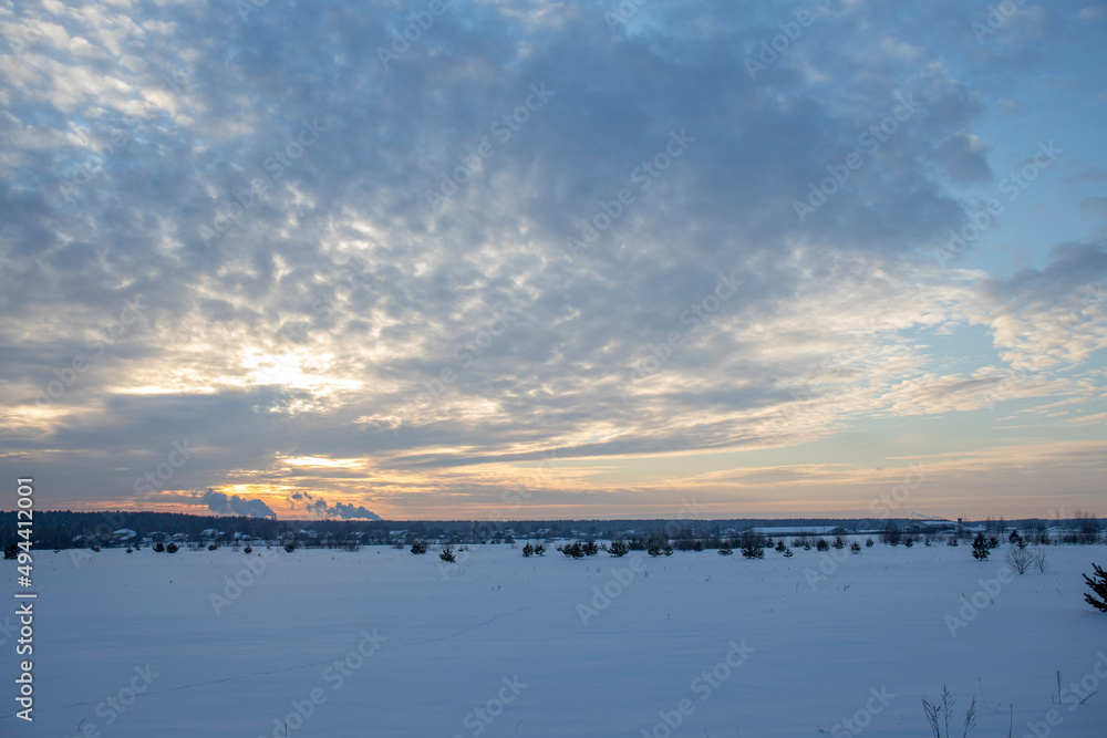 Winter minimalist landscape with colorful clouds in the sky and smoking chimneys on the horizon. winter tourism