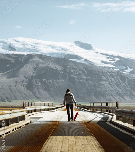 girl with skateboard in front of glacier