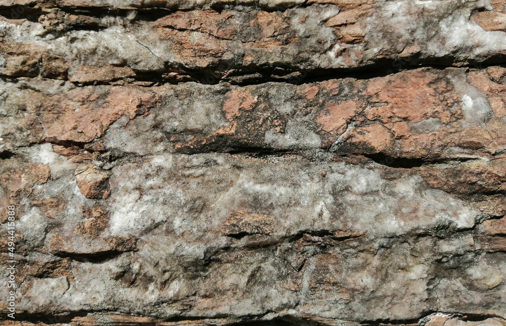 Layered, antique stonework with red and white ledges on it Layered, antique stonework with red and white ledges on it