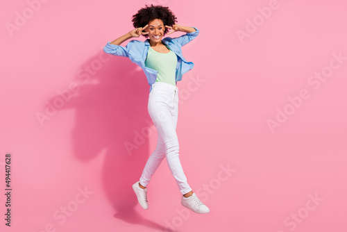 Photo of nice funky pretty lady jump show v-sign run wear denim shirt pants sneakers isolated pink color background © deagreez