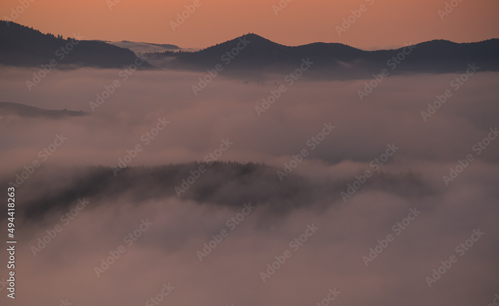 Amazing landscape during a foggy morning with the sea of clouds overs forests at the bottom of the mountains. Beautiful nature of the world.