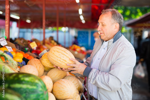 Man choosing melons in fruit shop