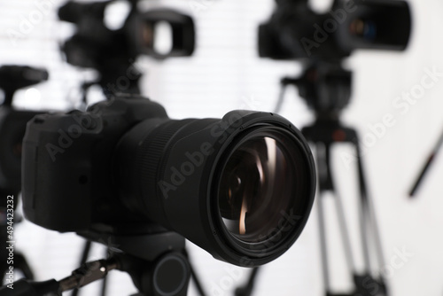 Modern video camera indoors, focus on lens. Professional media equipment for broadcasting event