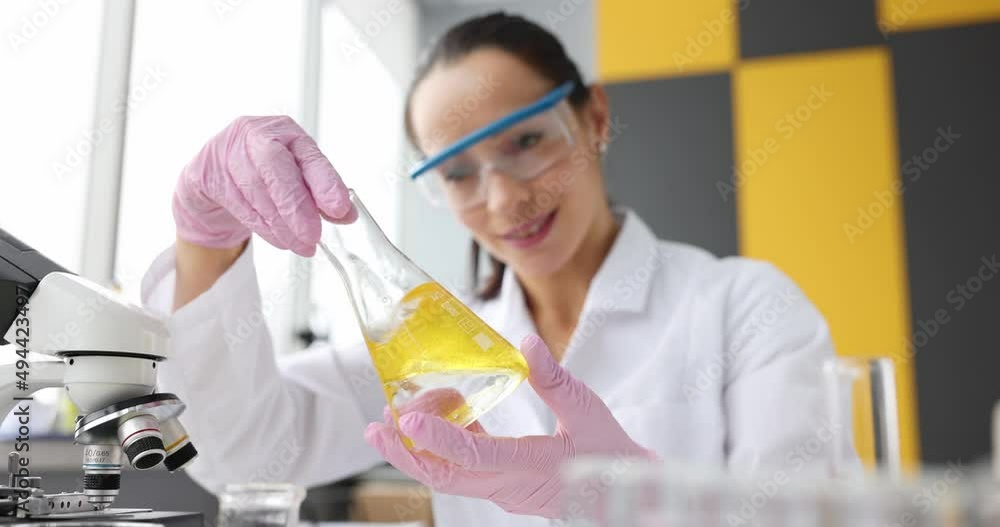 Scientist examines yellow transparent liquid in flask Scientist examines yellow transparent liquid in flask