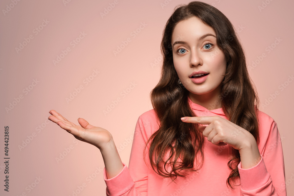 A young girl with long hair and blue eyes points her finger to the sides. A young girl with long hair and blue eyes points her finger to the sides.