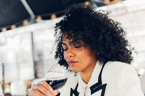 Fototapeta Woman sommelier tasting a glass of red wine in a wine cellar