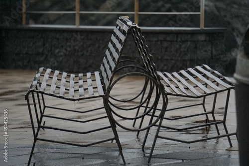 Panchina in ferro doppia sotto la pioggia, con fermo immagine delle gocce d'acqua che cadono   photo