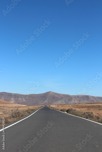 A straight long highway in the middle of nowhere with mountains in the background