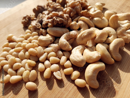 Mixed nuts - pine nuts, cashews, walnuts on a wooden board.