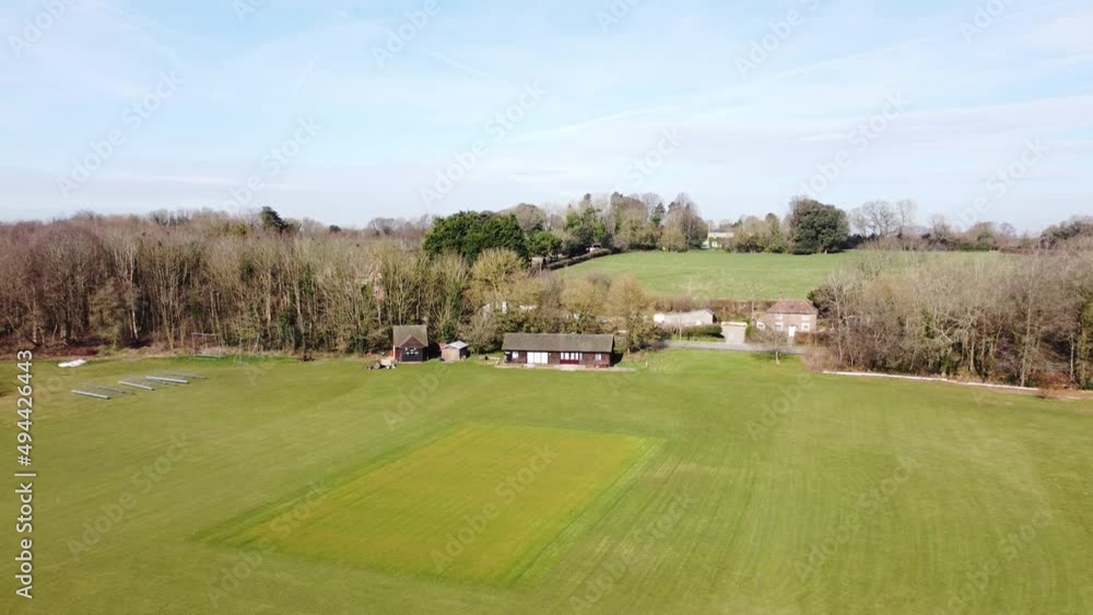 Nonington village cricket club house and green pitch aerial view rising pull back Nonington village cricket club house and green pitch aerial view rising pull back