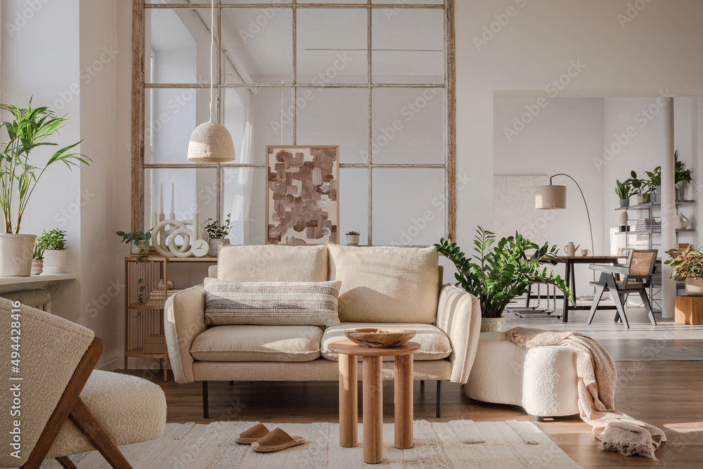 Fototapeta premium Elegant living room interior design with beige modern sofa, side table, painting and creative accessories. Template. Copy space. Dining room in the background.