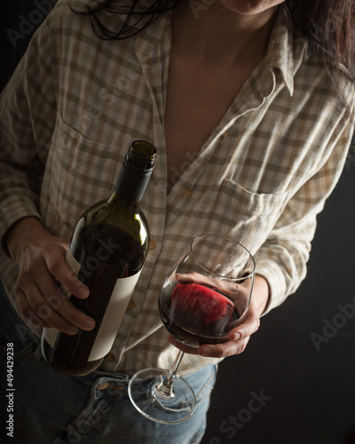 A woman with a plaid shirt pours red wine into a glass. photo