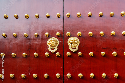 Antique traditional Chinese door style handle knocker with brass handles symbolic of lion head on red wood Door photo