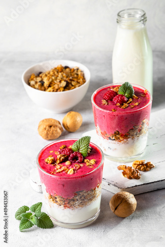 Yogurt, raspberry smoothie and homemade granola in a transparent glass. Healthy breakfast or snack. Copy space