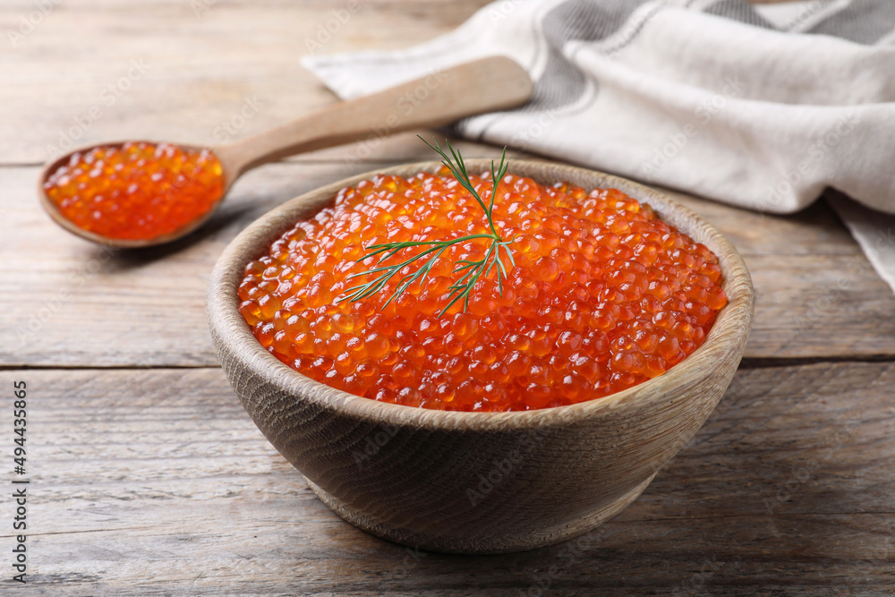Bowl and spoon with delicious red caviar on wooden table Bowl and spoon with delicious red caviar on wooden table