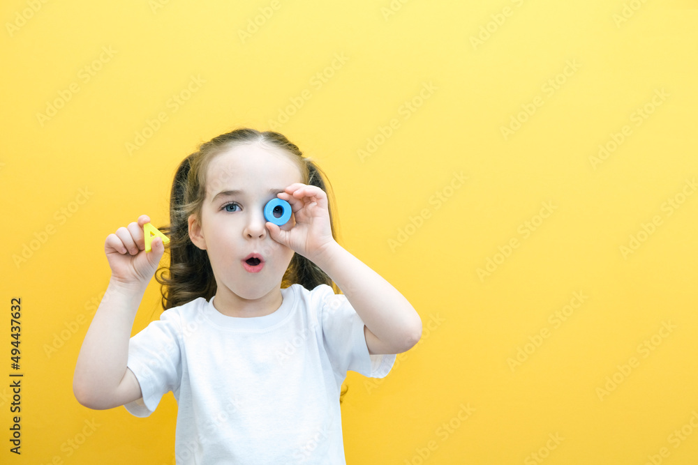 speech therapy. Toddler girl holding the letter O and A in her hands. Classes with a speech therapist. - obrazy, fototapety, plakaty 
