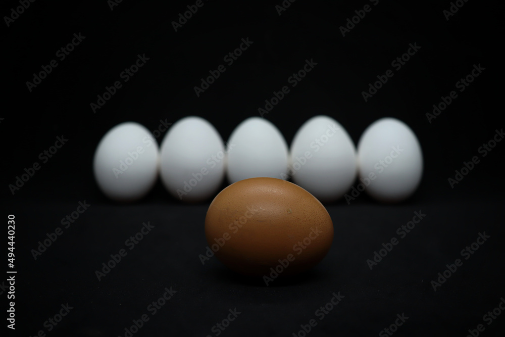 White and brown chicken eggs on a black background White and brown chicken eggs on a black background