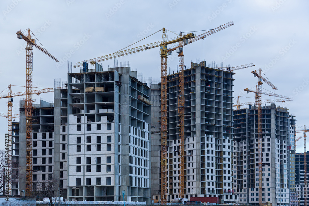 Construction site of multi-storey houses and building cranes Construction site of multi-storey houses and building cranes