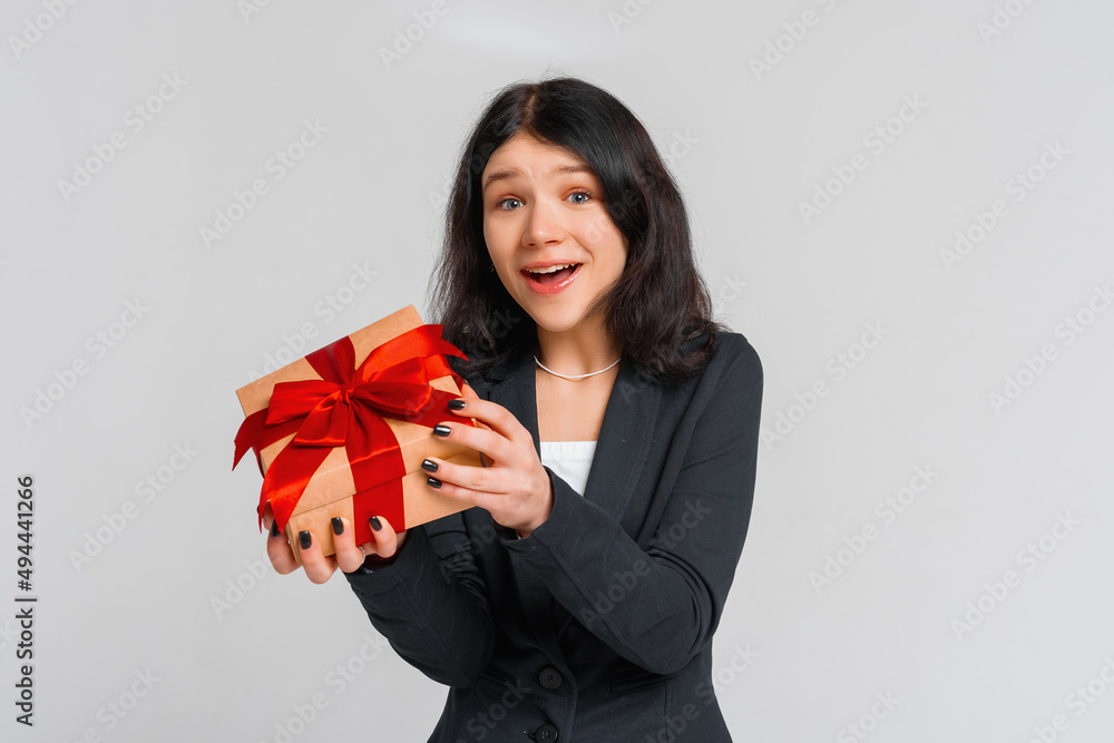 Happy excited brunette teenager girl in black blazer celebrating birthday, wonder whats inside b-day gift, opening box and smiling happy, grey background. lucky person Happy excited brunette teenager girl in black blazer celebrating birthday, wonder whats inside b-day gift, opening box and smiling happy, grey background. lucky person