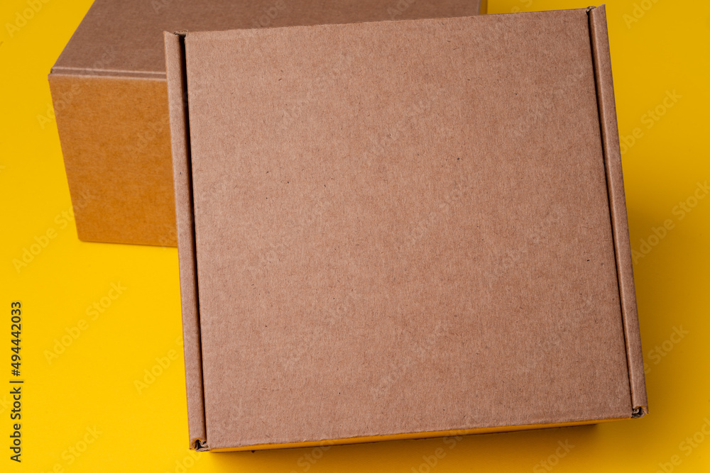 Fototapeta premium Beige cardboard boxes on yellow background, close up