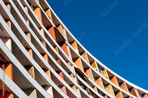 Curved old orange building against blue sky.
