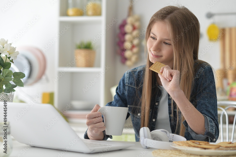 beautiful girl using laptop at home and drinkng tea with cookies beautiful girl using laptop at home and drinkng tea with cookies