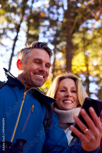 Mature Retired Couple Walk In Fall Or Winter Countryside Using Map Or Navigation App On Mobile Phone photo