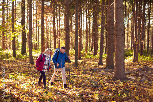 Side View Of Mature Retired Couple Walking Through Fall Or Winter Countryside Using Hiking Poles