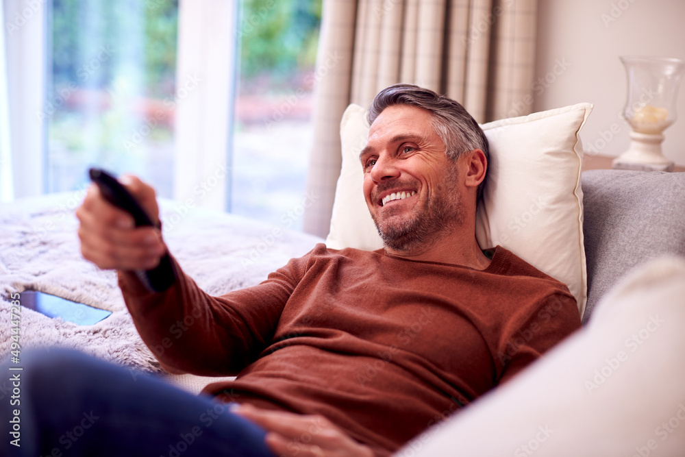 Mature Man At Home Relaxing On Sofa Watching TV Using Remote Control Mature Man At Home Relaxing On Sofa Watching TV Using Remote Control