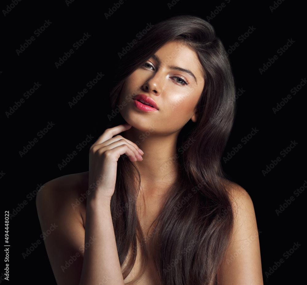 Obraz premium Flawless skin and great hair make a formidable package. Studio shot of a beautiful woman touching her chin posing against a black background.