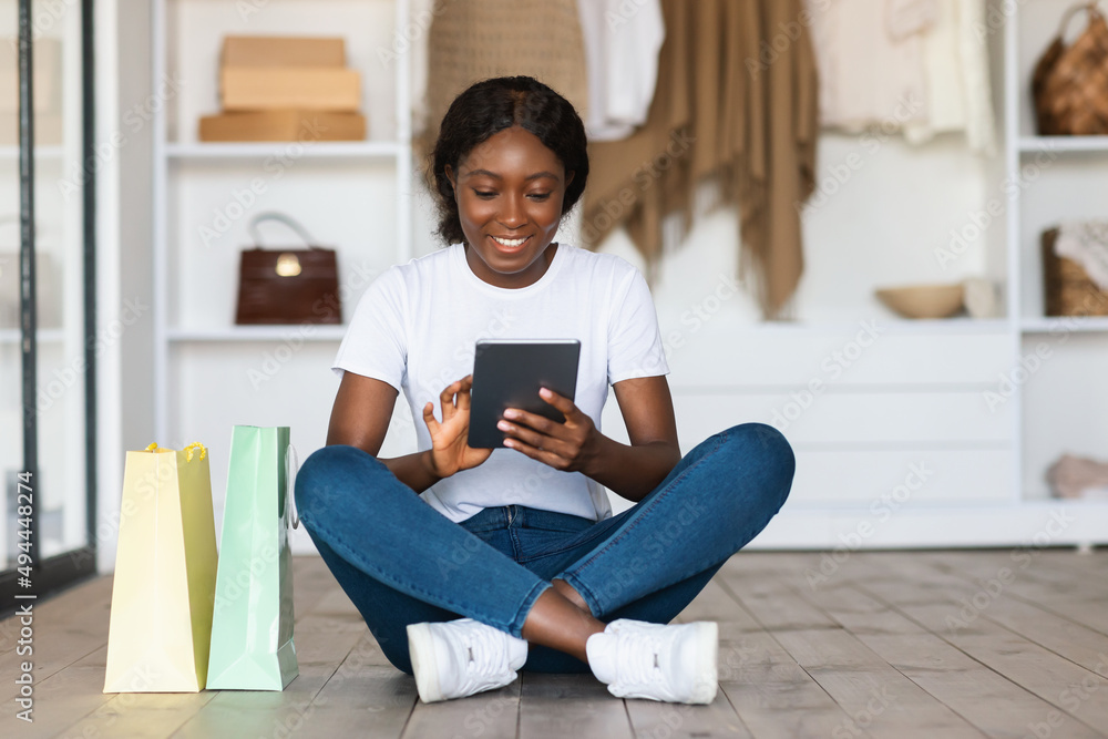 African Lady Shopping Using Digital Tablet Sitting On Floor Indoor African Lady Shopping Using Digital Tablet Sitting On Floor Indoor