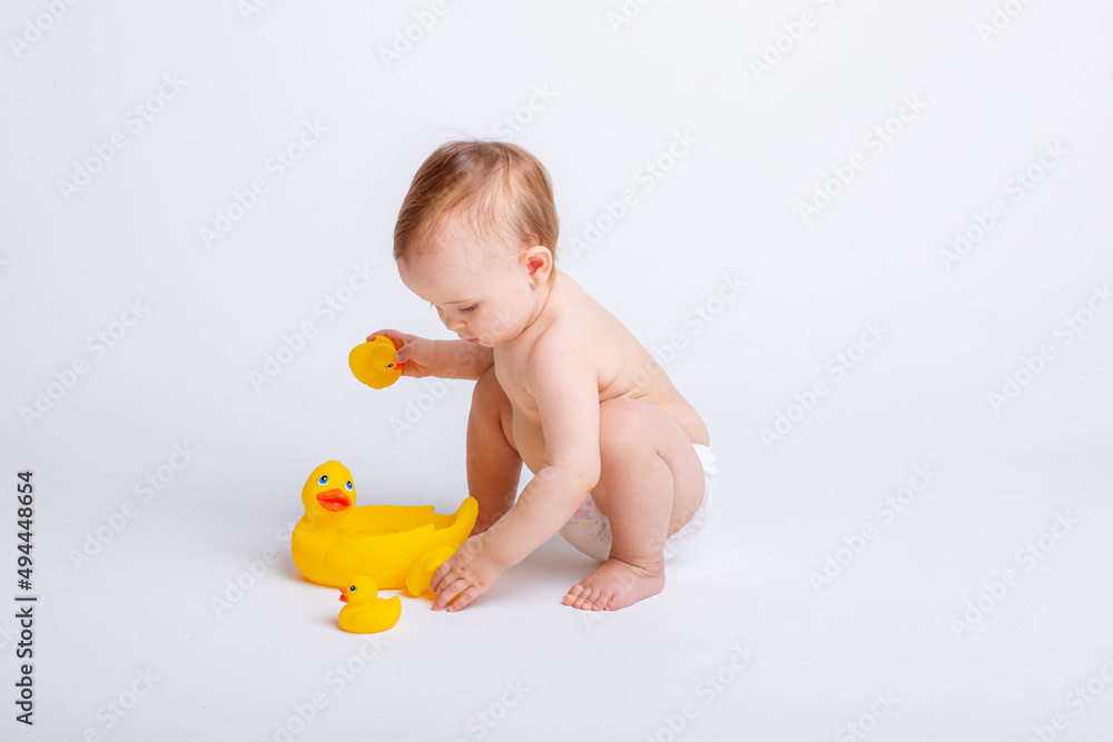 cute baby girl in a diaper playing with a rubber toy duck isolated on a white background cute baby girl in a diaper playing with a rubber toy duck isolated on a white background