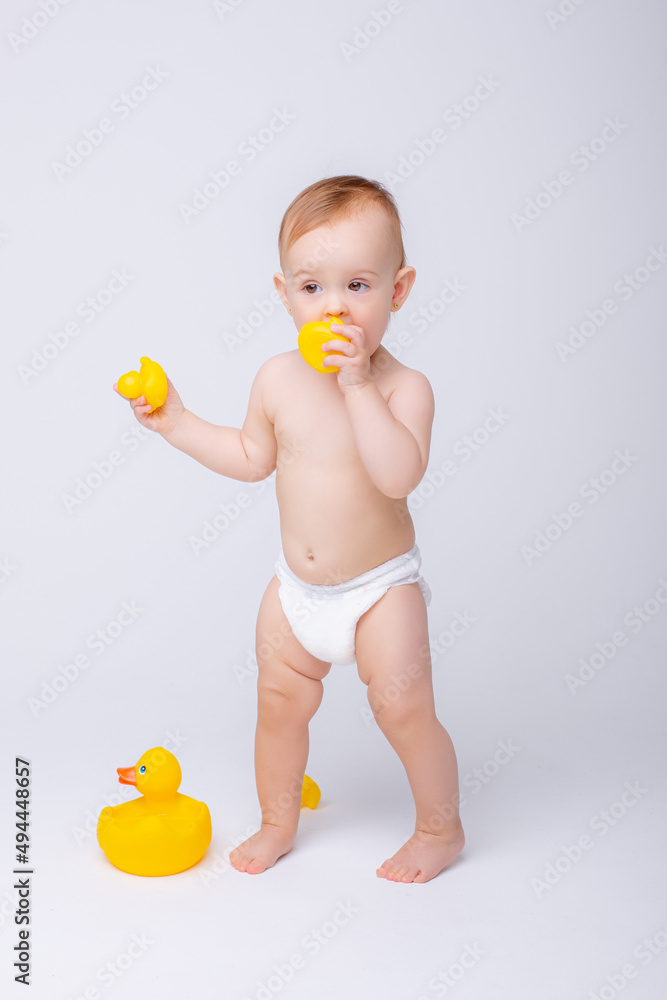 cute baby girl in a diaper playing with a rubber toy duck isolated on a white background cute baby girl in a diaper playing with a rubber toy duck isolated on a white background