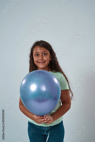 Latin little girl hold balloon and look at camera