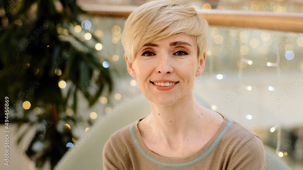 Head shot middle aged caucasian blonde woman with short hairstyle indoors  smile white teeth looks at camera feels confident and happy 40s female  teacher manager mother wife with positive face portrait Stock