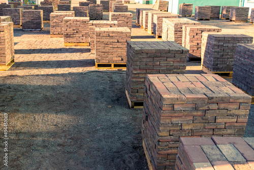 dismantled paving slabs or paving stones are stacked on pallets in the middle of the site waiting for removal