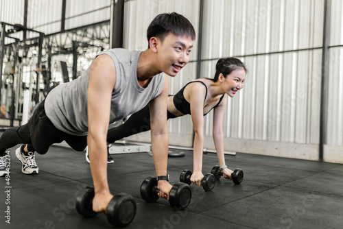 exercise concept The female and male members of the gym doing the basic renegade row posture with dumbbells while looing at each other   s face