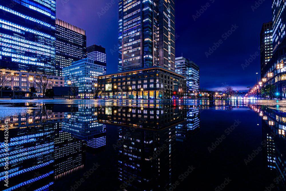 Obraz premium Night city view of business buildings around the Marunouchi side of Tokyo Station after rain. Reflection photo with beautiful specular reflection.