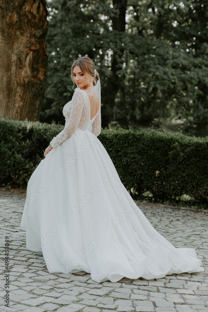 Gorgeous stylish bride in vintage white dress walking in the park