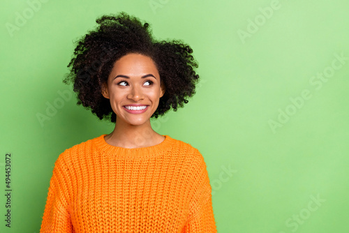 Photo of impressed young volume hairdo lady look promo wear orange sweater isolated on green color background