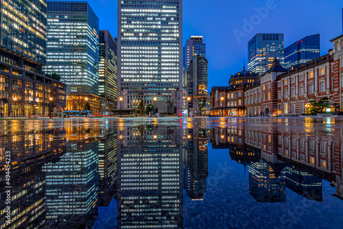Night city view of business buildings around the Marunouchi side of Tokyo Station after rain. Reflection photo with beautiful specular reflection.