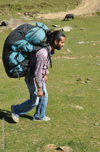 Full length side view of a young man walking in the mountain with carrying parachute backpack