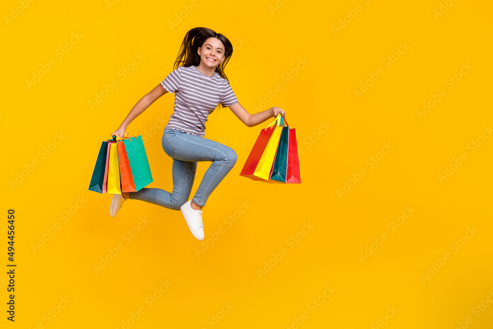 Full body profile side photo of young girl hold shopping bag run hurry isolated over yellow color background Full body profile side photo of young girl hold shopping bag run hurry isolated over yellow color background