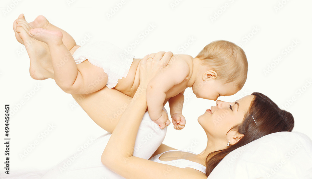 Portrait of happy young mother and cute baby lying on the bed at home together on white background Portrait of happy young mother and cute baby lying on the bed at home together on white background