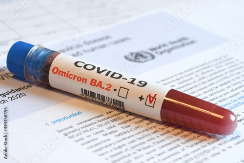 Blood tube for test detection of virus Covid-19 Omicron BA.2 Variant with positive result on papers document.