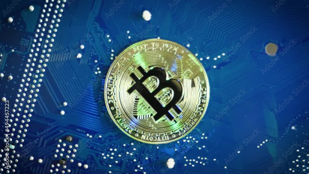 Single Bitcoin on Computer blue board rotating, Mining Bitcoins concept, Topdown shot Single Bitcoin on Computer blue board rotating, Mining Bitcoins concept, Topdown shot