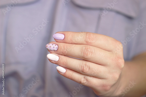 purple glamor manicure long nails with crystals one hand on a lilac background