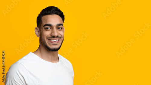 Portrait of cheerful handsome middle eastern young man on yellow